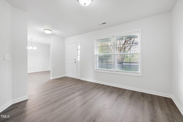 foyer entrance featuring baseboards, dark wood-style flooring, visible vents, and a chandelier