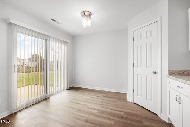 spare room featuring baseboards, light wood finished floors, and visible vents
