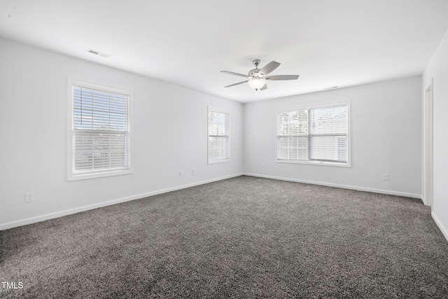 empty room featuring dark carpet, baseboards, visible vents, and a ceiling fan