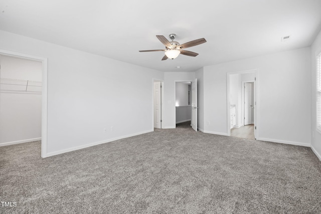 unfurnished bedroom featuring a spacious closet, carpet, baseboards, and visible vents