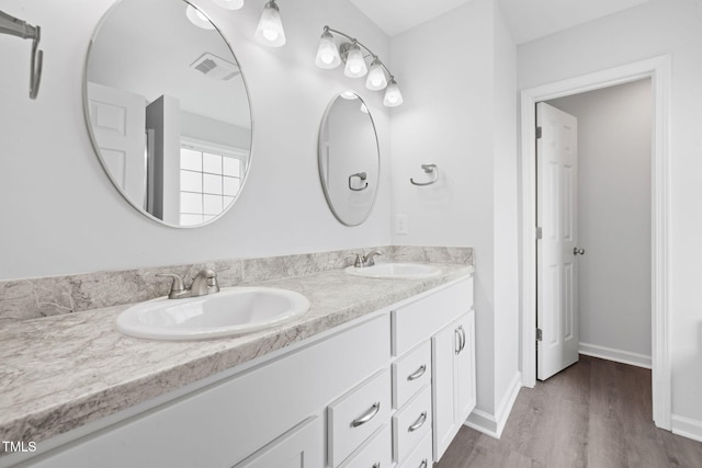 bathroom featuring double vanity, a sink, wood finished floors, and visible vents