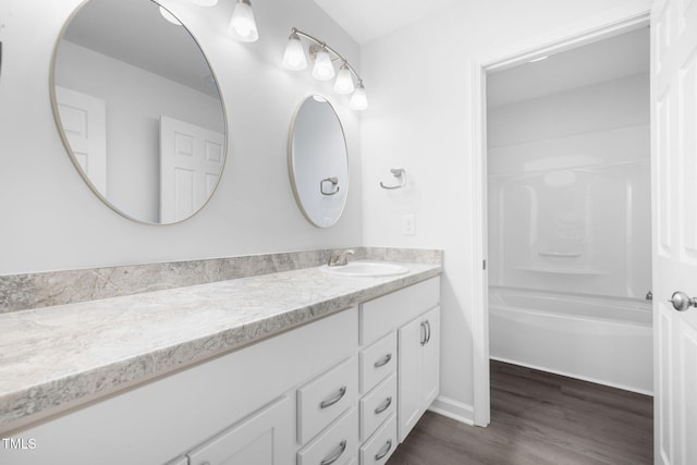 full bathroom featuring baseboards, wood finished floors, shower / tub combination, and vanity