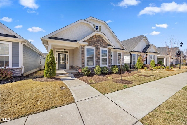 craftsman-style house featuring stone siding and a front yard