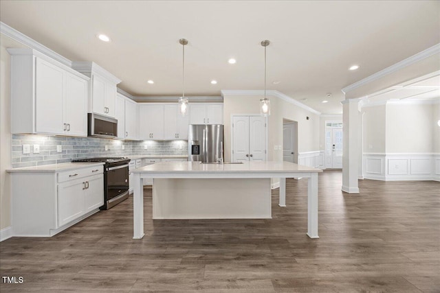 kitchen featuring crown molding, an island with sink, white cabinetry, light countertops, and appliances with stainless steel finishes