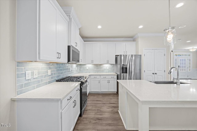 kitchen featuring white cabinets, ornamental molding, stainless steel appliances, and a sink