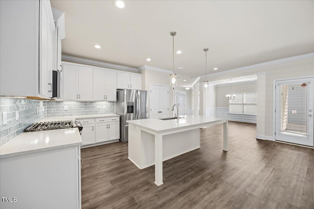 kitchen with stainless steel appliances, light countertops, a sink, crown molding, and a kitchen island with sink