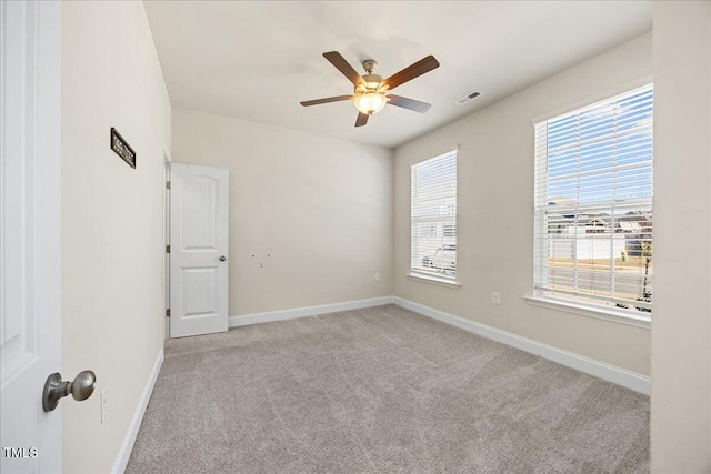 unfurnished room with carpet floors, visible vents, a ceiling fan, and baseboards