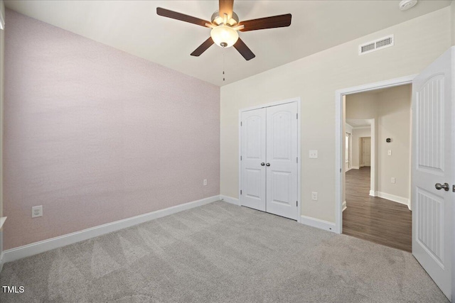 unfurnished bedroom featuring baseboards, visible vents, a ceiling fan, a closet, and carpet floors