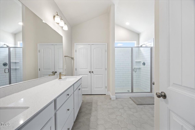 full bathroom featuring lofted ceiling, a sink, a shower stall, and double vanity