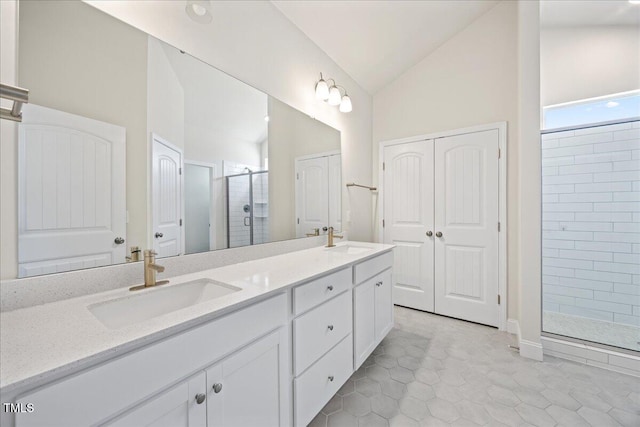 bathroom with vaulted ceiling, a sink, a shower stall, and double vanity