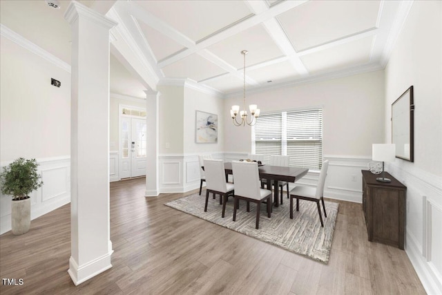 dining room featuring wainscoting, coffered ceiling, a decorative wall, and decorative columns