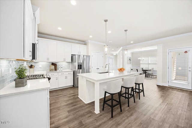 kitchen with light countertops, a sink, crown molding, a breakfast bar, and appliances with stainless steel finishes