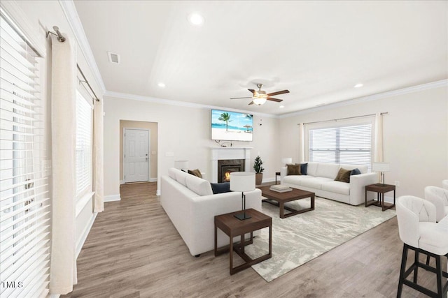 living room featuring recessed lighting, visible vents, a ceiling fan, light wood-style floors, and a glass covered fireplace