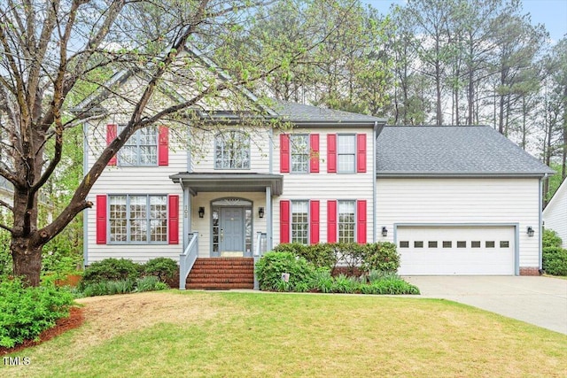 colonial house with driveway, a front lawn, a garage, and roof with shingles