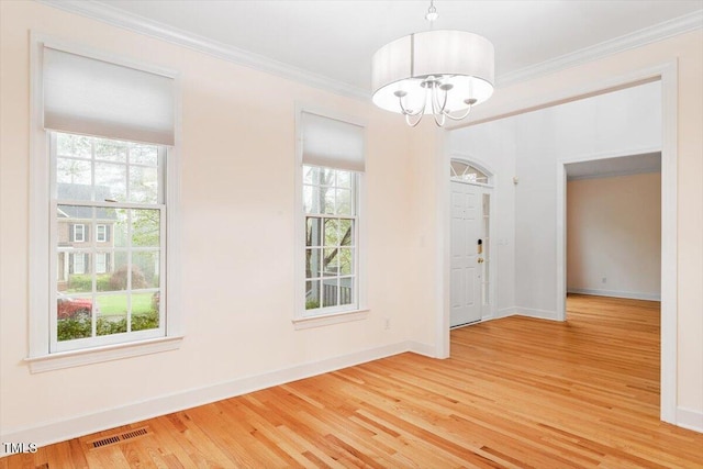 unfurnished dining area with a chandelier, light wood-style flooring, healthy amount of natural light, crown molding, and baseboards