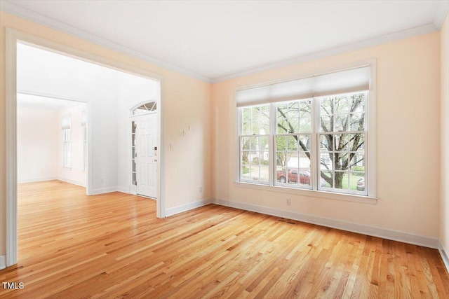 spare room featuring ornamental molding, light wood-type flooring, and baseboards