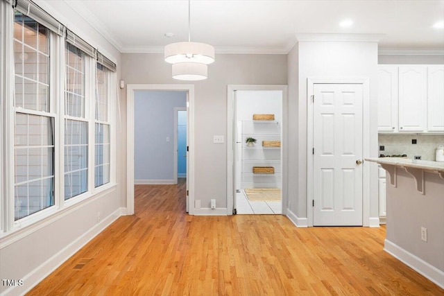 unfurnished dining area with light wood-style floors, baseboards, crown molding, and recessed lighting