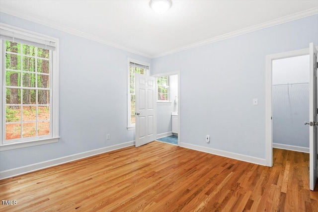 unfurnished room featuring baseboards, light wood finished floors, and crown molding