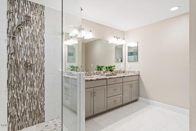 full bath with walk in shower, double vanity, marble finish floors, and baseboards