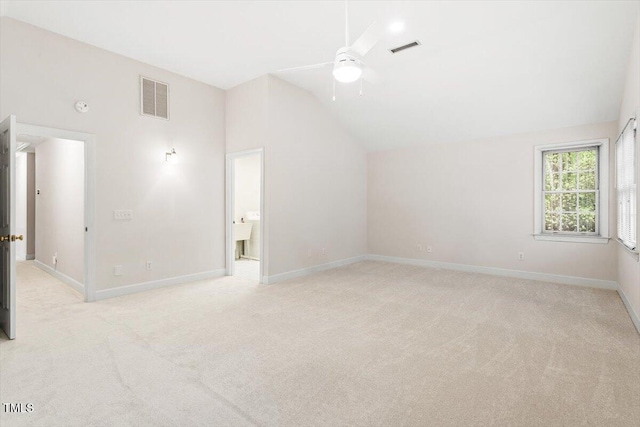 spare room featuring lofted ceiling, light carpet, a ceiling fan, and baseboards