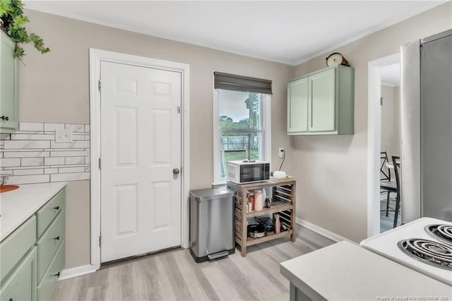 1002 Hicks Ave, Fayetteville, NC 28304 - kitchen with green cabinets, light countertops, tasteful backsplash, baseboards, and light wood finished floors