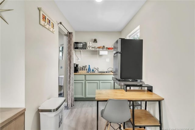1002 Hicks Ave, Fayetteville, NC 28304 - kitchen featuring green cabinetry, a sink, freestanding refrigerator, open shelves, and light wood-style floors