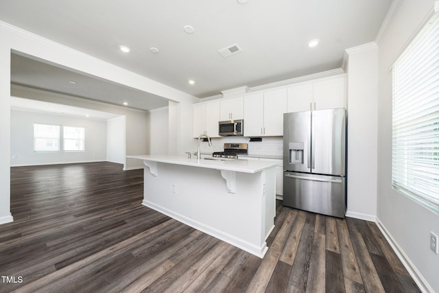 3025 Castle Loch Ln, Durham, NC 27703 - kitchen featuring stainless steel appliances, light countertops, an island with sink, dark wood-type flooring, and ornamental molding