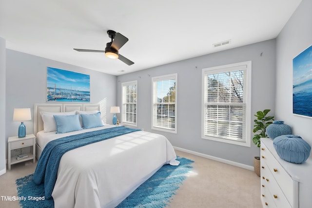 bedroom featuring light colored carpet, visible vents, baseboards, and ceiling fan