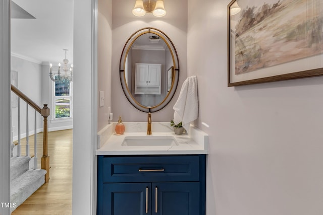 bathroom with a chandelier, wood finished floors, vanity, and ornamental molding