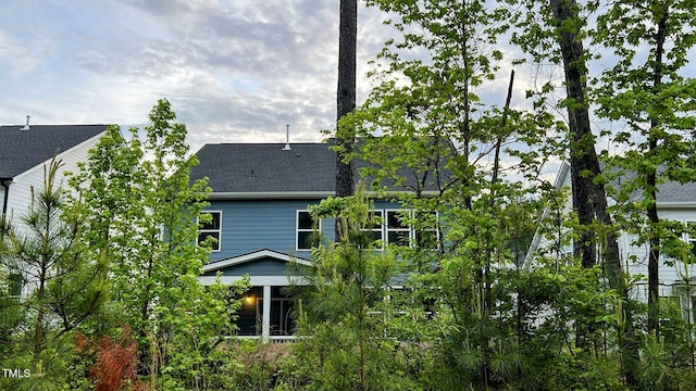 view of side of property with a shingled roof and a sunroom
