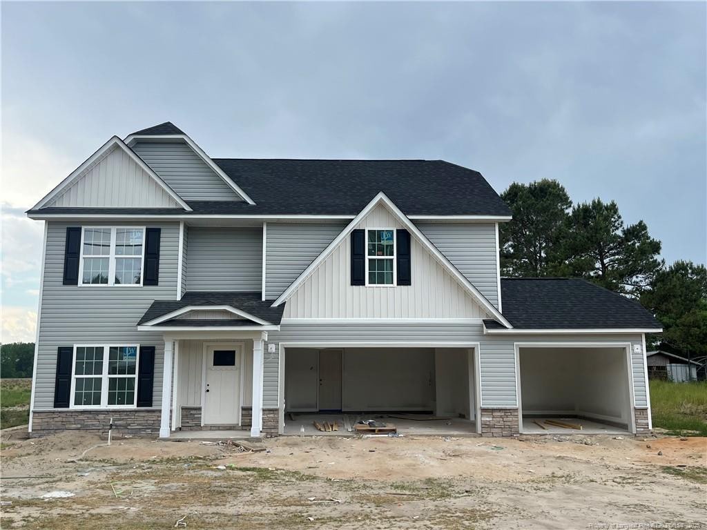 1232 Chason Rd, Lumber Bridge, NC 28357 - view of front of house featuring roof with shingles, stone siding, driveway, a garage, and board and batten siding