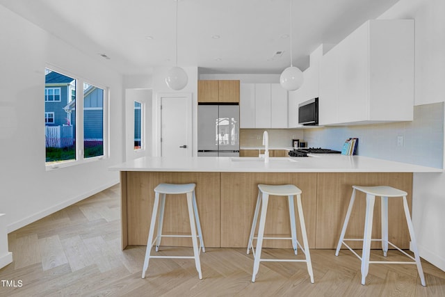 kitchen with a peninsula, light countertops, fridge, and a sink