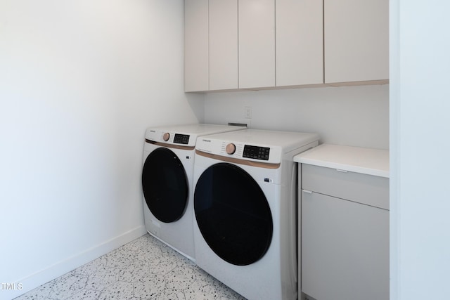 washroom featuring washer and clothes dryer, cabinet space, and baseboards