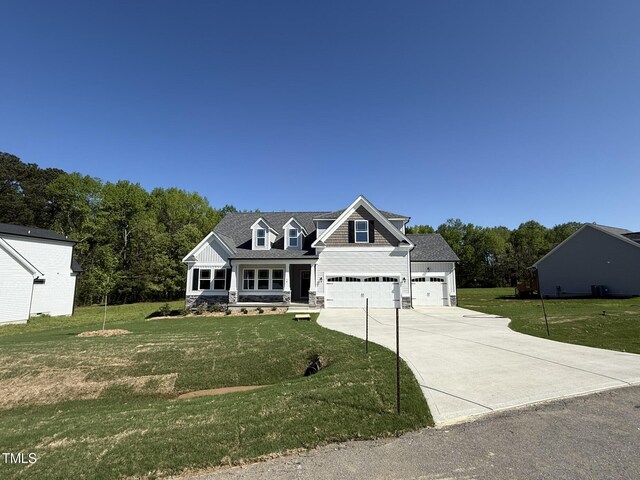 view of front facade featuring a front yard, a shingled roof, a porch, a garage, and concrete driveway