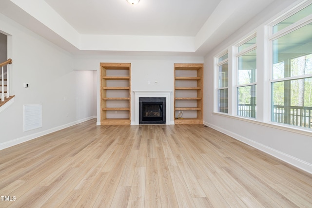 50 Gadwall Ct, Zebulon, NC 27597 - unfurnished living room with a raised ceiling, a fireplace, light wood-type flooring, and stairs