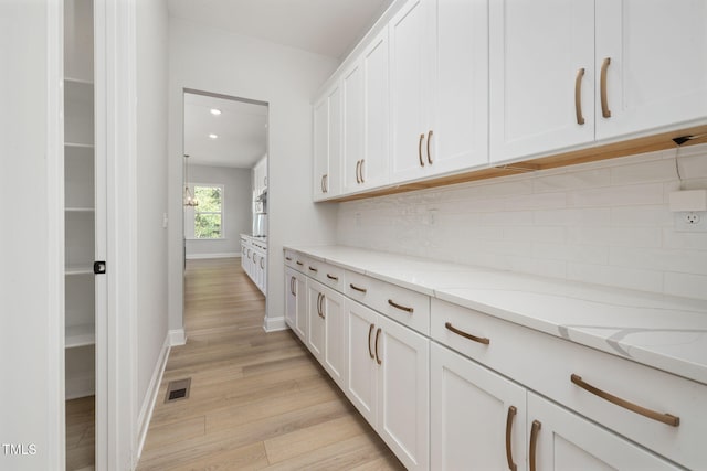 50 Gadwall Ct, Zebulon, NC 27597 - kitchen with light wood finished floors, white cabinetry, baseboards, backsplash, and visible vents