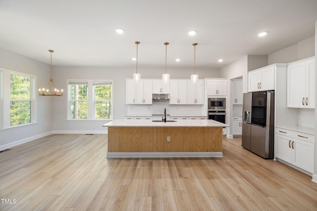 50 Gadwall Ct, Zebulon, NC 27597 - kitchen featuring light wood-type flooring, light countertops, under cabinet range hood, and stainless steel appliances