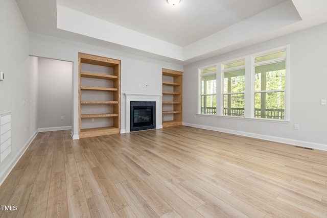 50 Gadwall Ct, Zebulon, NC 27597 - unfurnished living room featuring baseboards, light wood-type flooring, built in shelves, and visible vents