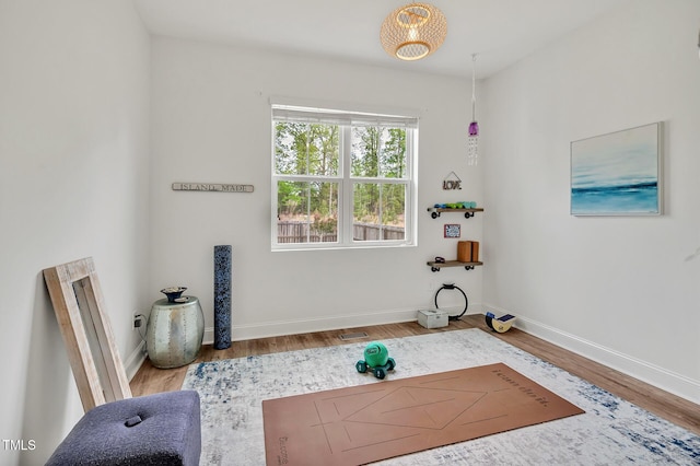 exercise area with visible vents, baseboards, and wood finished floors