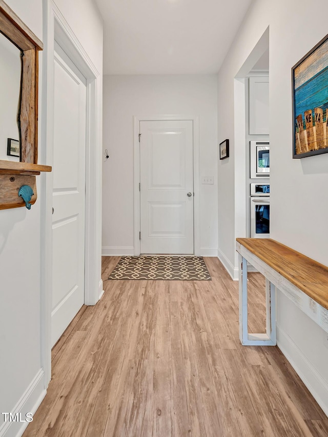 hall featuring baseboards and light wood finished floors