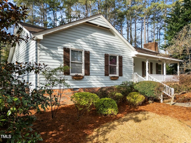 view of side of property featuring a porch, crawl space, stairway, and a chimney