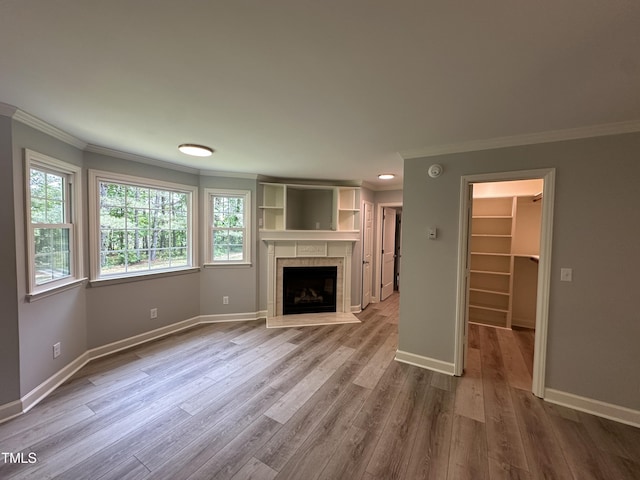 unfurnished living room featuring baseboards, ornamental molding, a healthy amount of sunlight, and a fireplace
