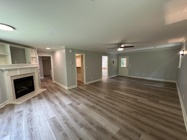 unfurnished living room featuring ornamental molding, a ceiling fan, wood finished floors, and a fireplace
