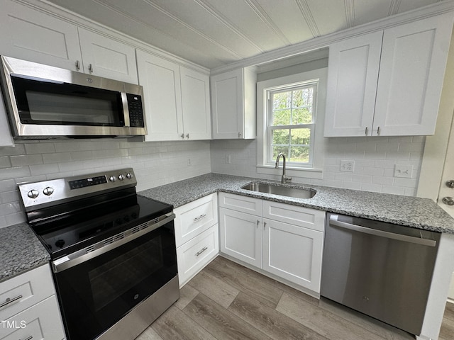 kitchen with white cabinets, stainless steel appliances, backsplash, and a sink