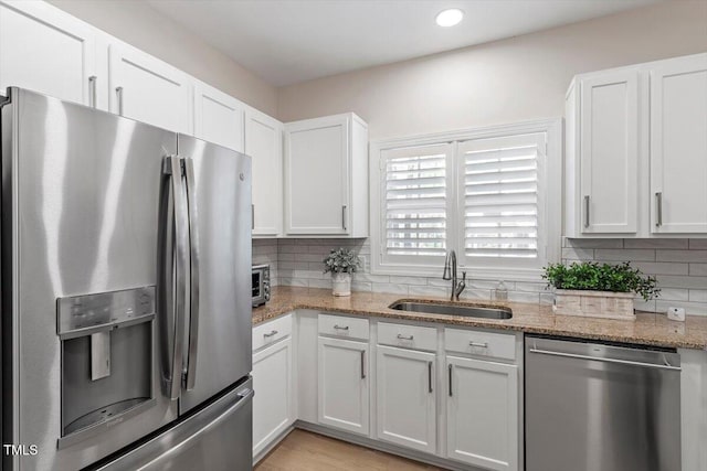 kitchen featuring white cabinets, a sink, tasteful backsplash, and appliances with stainless steel finishes