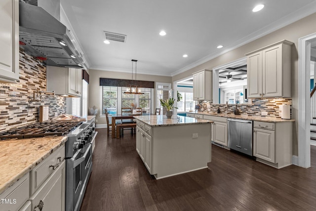 kitchen featuring visible vents, decorative backsplash, a kitchen island, wall chimney exhaust hood, and stainless steel appliances