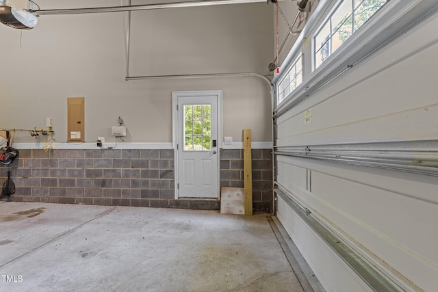 garage featuring wainscoting, a garage door opener, and electric panel