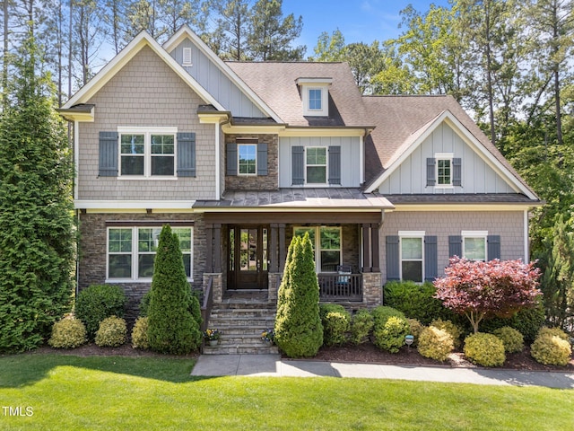 craftsman-style home with a porch, board and batten siding, a standing seam roof, a front lawn, and a shingled roof