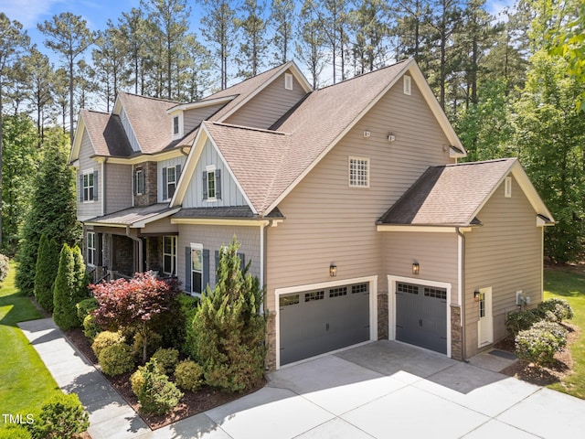 view of front facade featuring stone siding, an attached garage, driveway, and roof with shingles