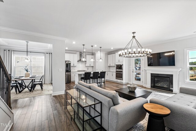 living area featuring a chandelier, crown molding, baseboards, recessed lighting, and dark wood-style floors